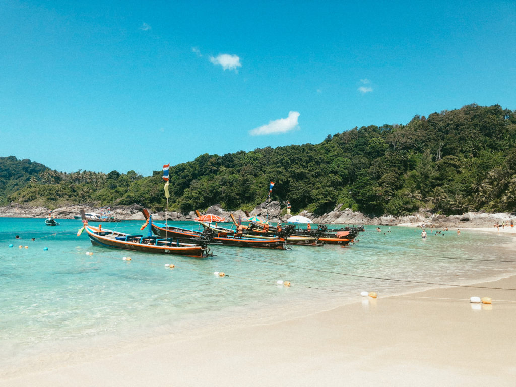 Small boats in clear blue water in Phuket, Thailand.