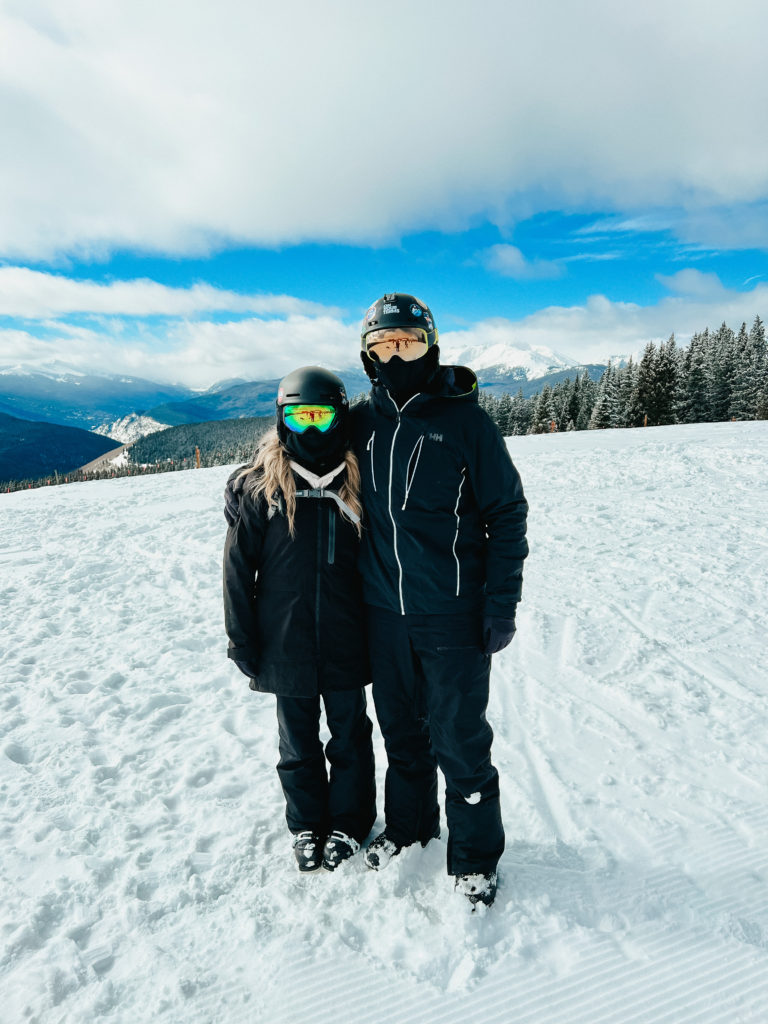 Abby and Sam standing on the ski slopes in Colorado with the best neck gaiters for snowboarding on.