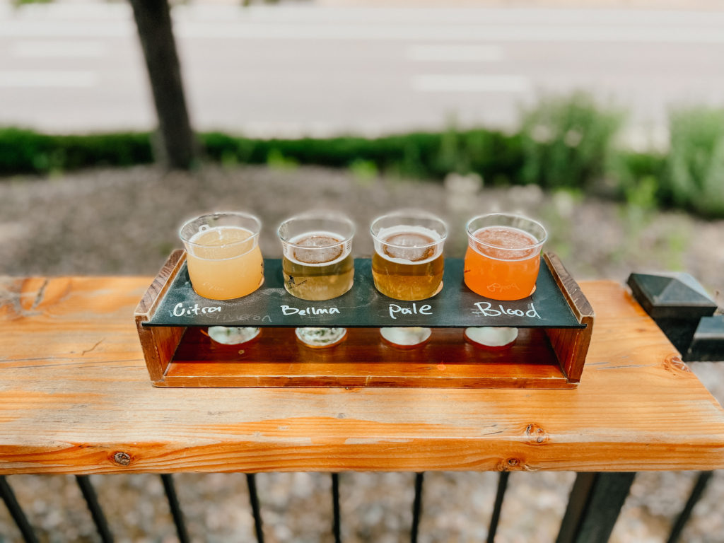 A flight of beer served outdoors on the patio of a brewery.