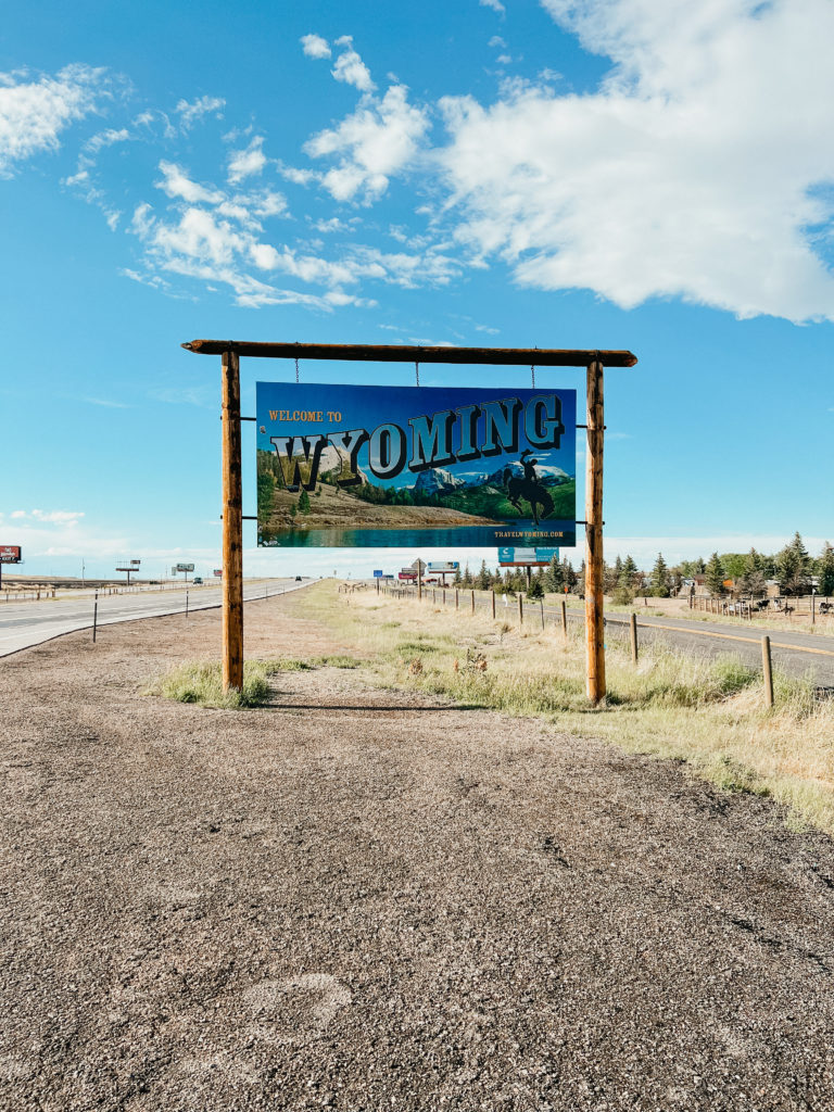 The Wyoming welcome sign with blue skies up above.