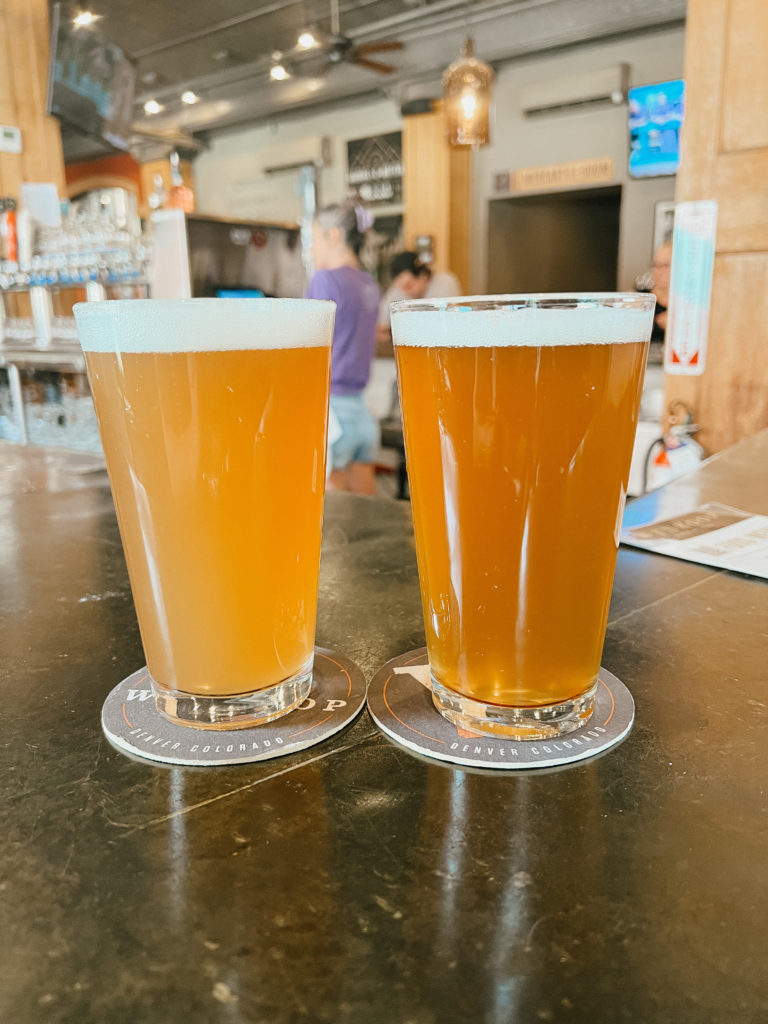 Two hazy craft beers sitting on a bar. 