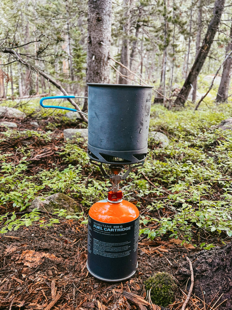 A small camping stove set up in the wilderness.