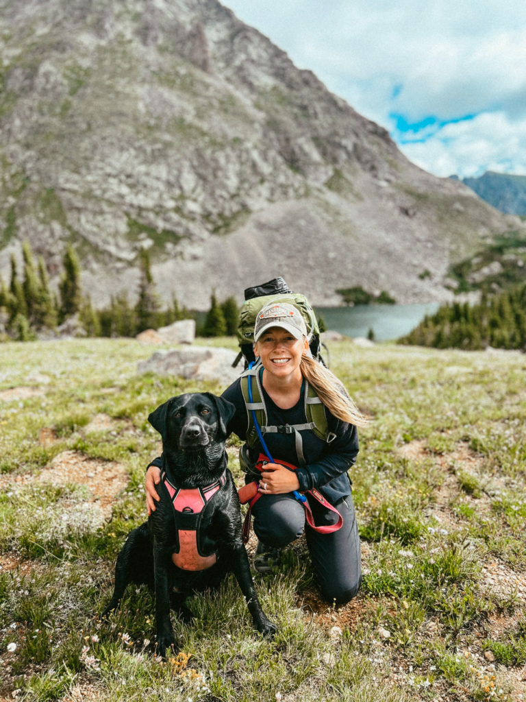 Abby and Clover backpacking in Colorado with mountains in the distance.