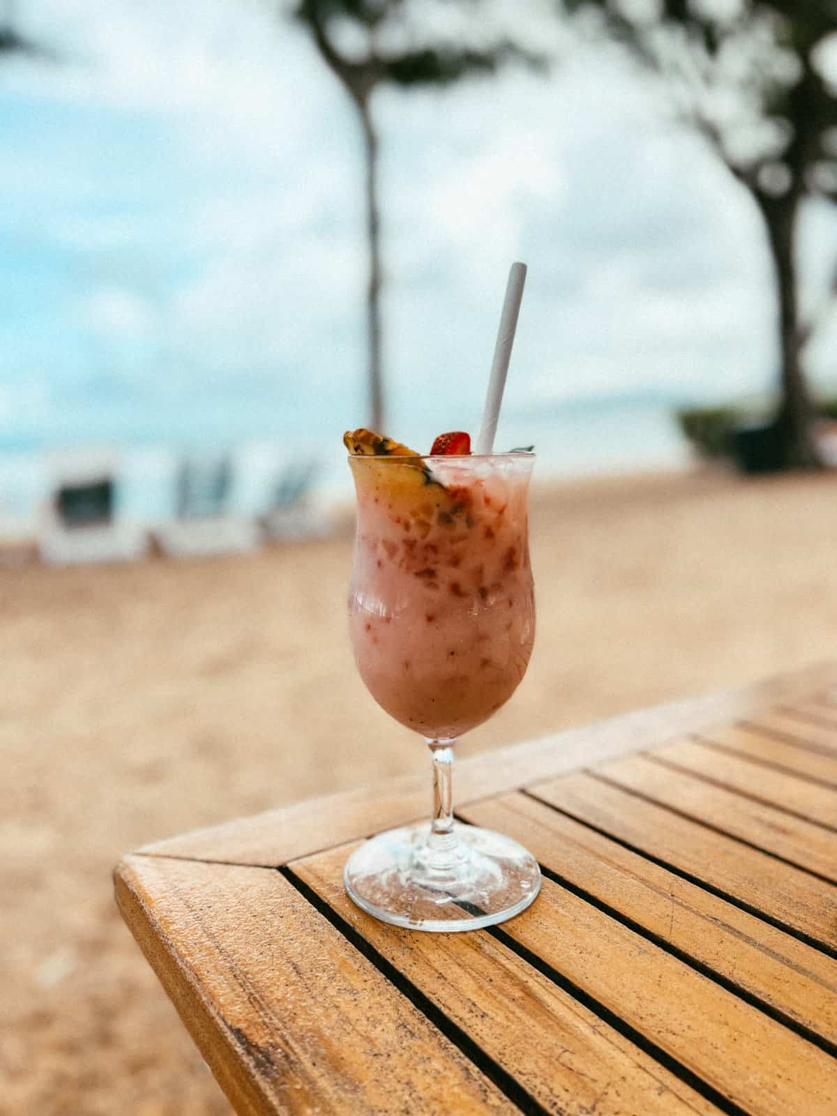 A strawberry and pineapple cocktail served with the ocean in the background.