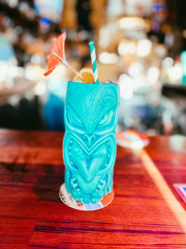 A blue tiki cocktail served with an umbrella.