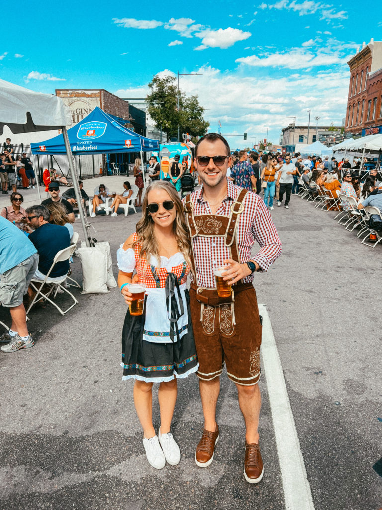 Abby and Sam smiling with Oktoberfest gear on in Denver.