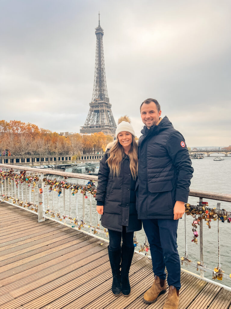 Abby and Sam smiling in front of the Eiffel Tower.