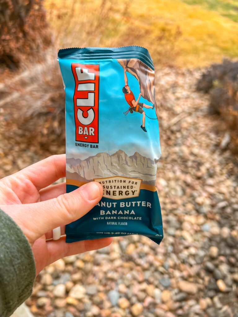 A Clif Bar with greenery in the background.