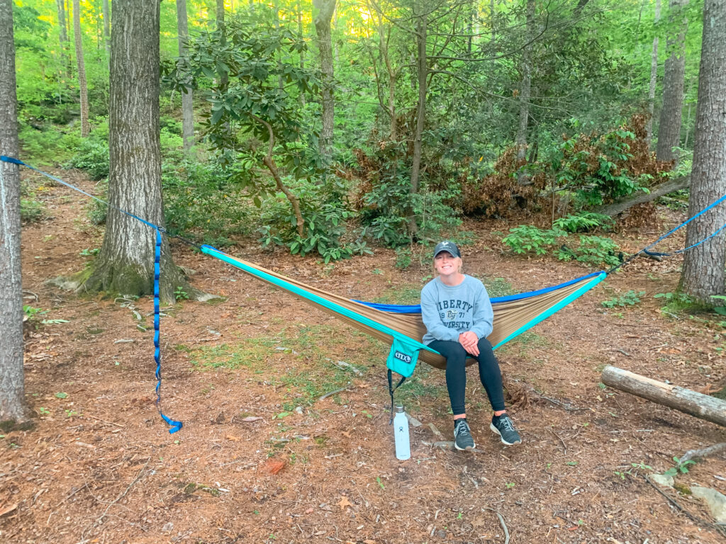 Abby smiling while sitting on the best 2 person camping hammock. 