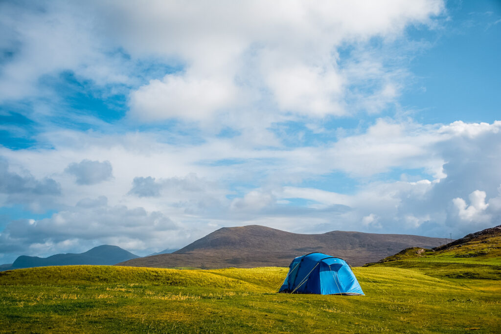 A tent set up in a green field with mountains in the background.