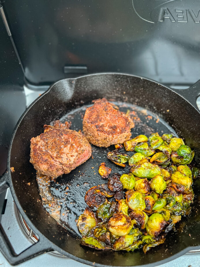 One of the best frying pans for camping on a portable camping stove cooking brussel sprouts and steaks.