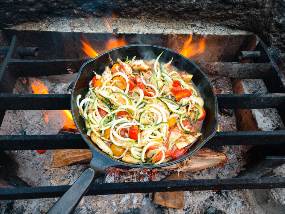 A cast iron skillet, one of the best frying pans for camping, filled with veggies.