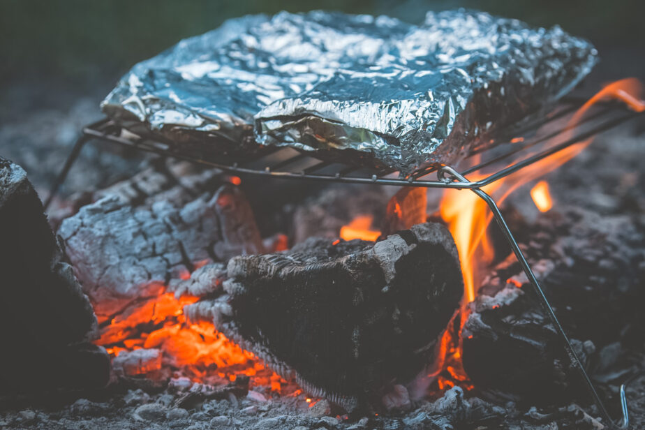 One of the best ways to heat food up over a campfire is by placing the food inside of foil and placing it on top of a foldable grill. 