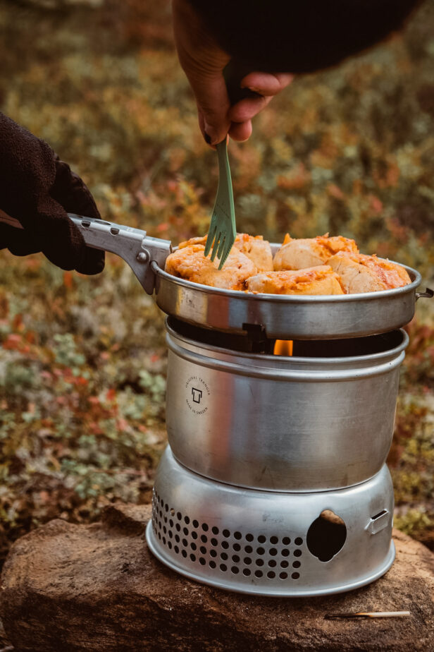 Someone cooking over a portable camping stove.