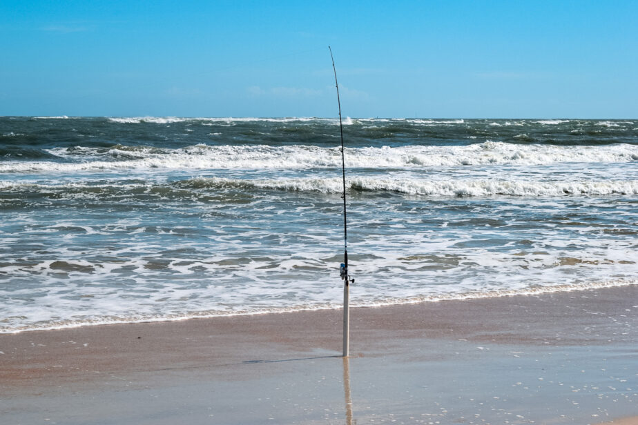 A surf fishing rod set up in the sand with the best surf fishing line ready to cast and reel in a big fish.