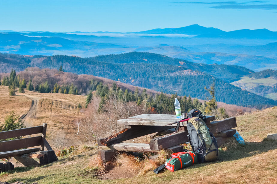 Backpacking gear set beside a picnic table with mountains in the distance.