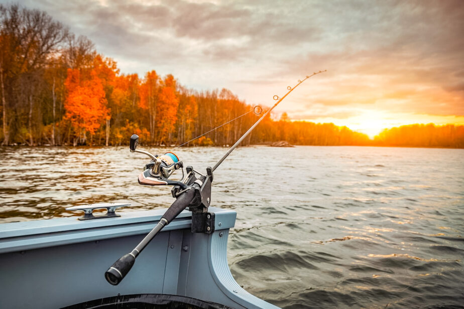 One of the best surf fishing reels set up on a boat on the water as the sun begins to rise in the distance.