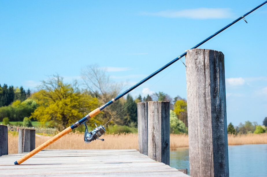 One of the best surf fishing reels set up on a rod and leaning on a dock.