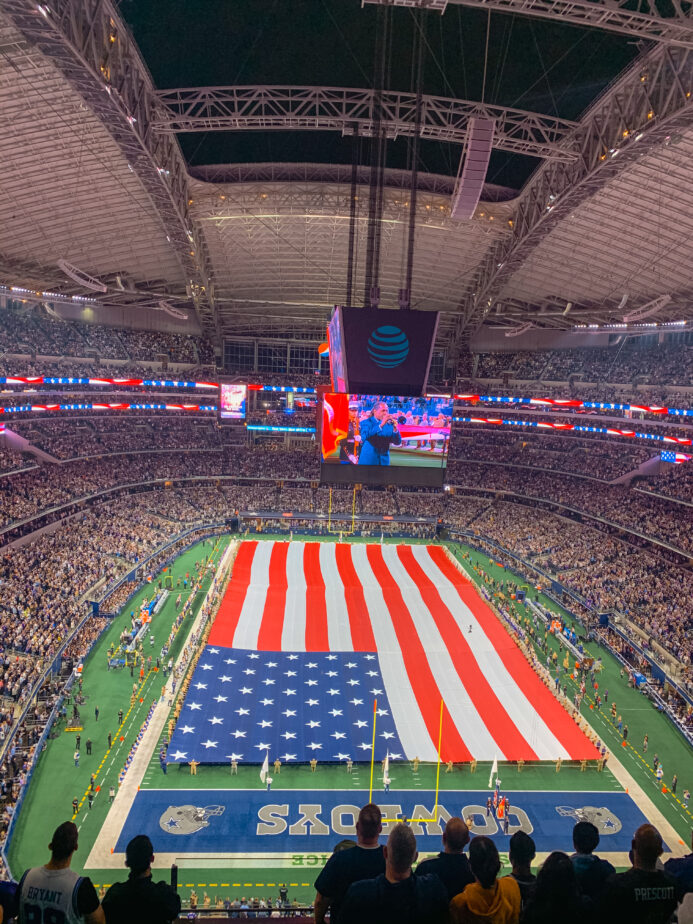 An American Flag spread out over the Dallas Cowboys football field.