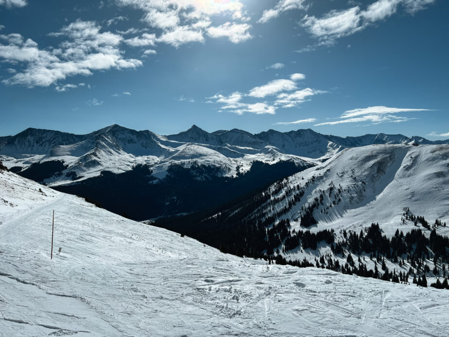 Ski slopes in Colorado with blue skies mixed with clouds up above.