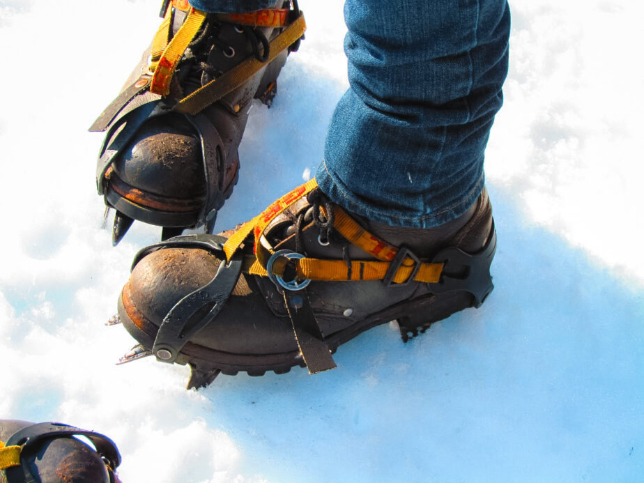 Crampons strapped on to hiking boots in the snow.