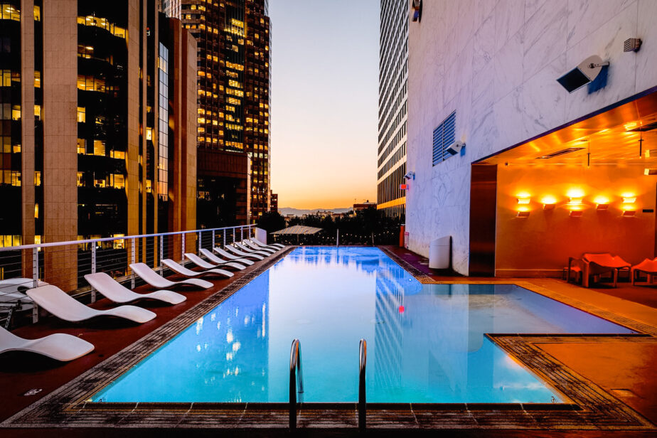 A rooftop pool with city views and mountains off in the distance.