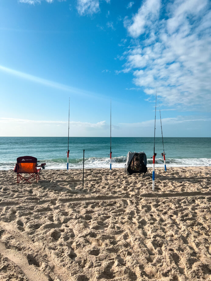 Surf fishing rods set up on the beach with one of the best saltwater tackle boxes.