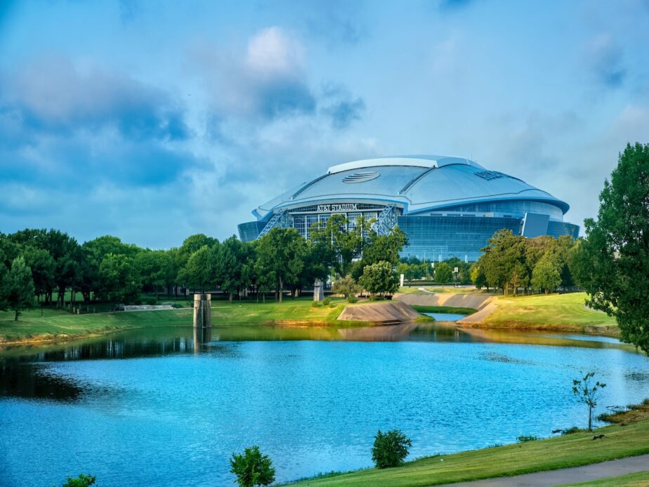 The Dallas Cowboys Stadium with a pond nearby.