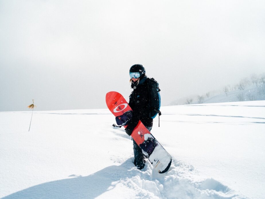 A snowboarder walking in the snow.