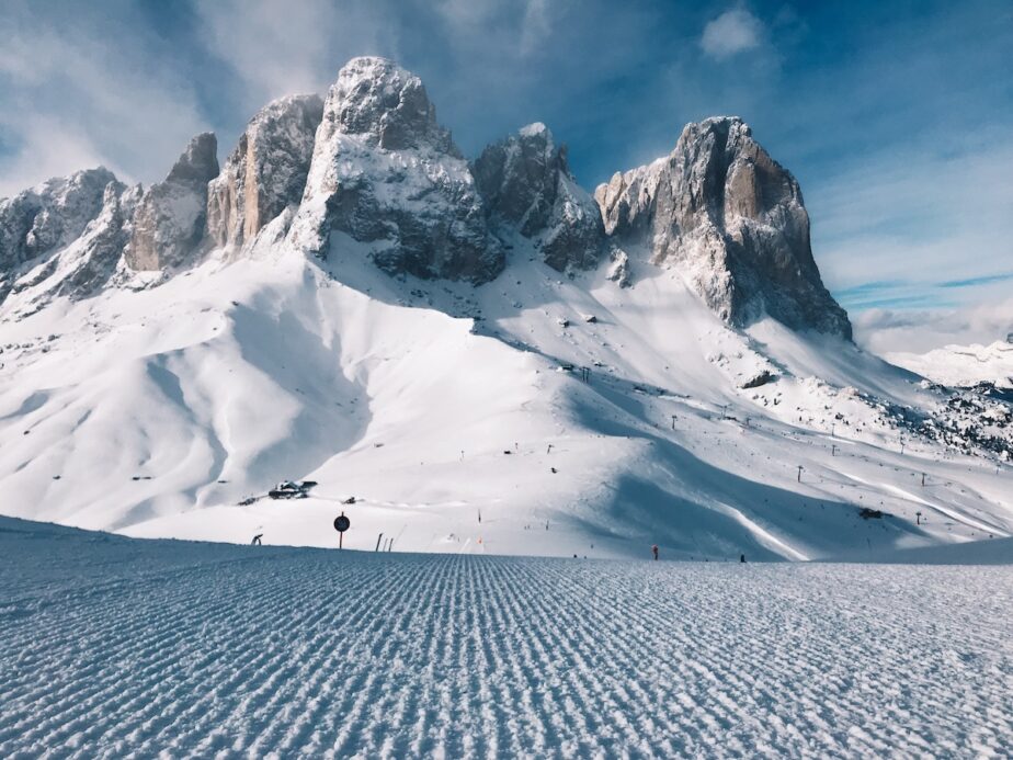 A groomed slope with mountains in the background.