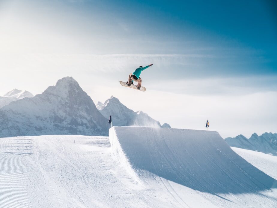 A snowboarder jumping with blue skies above.