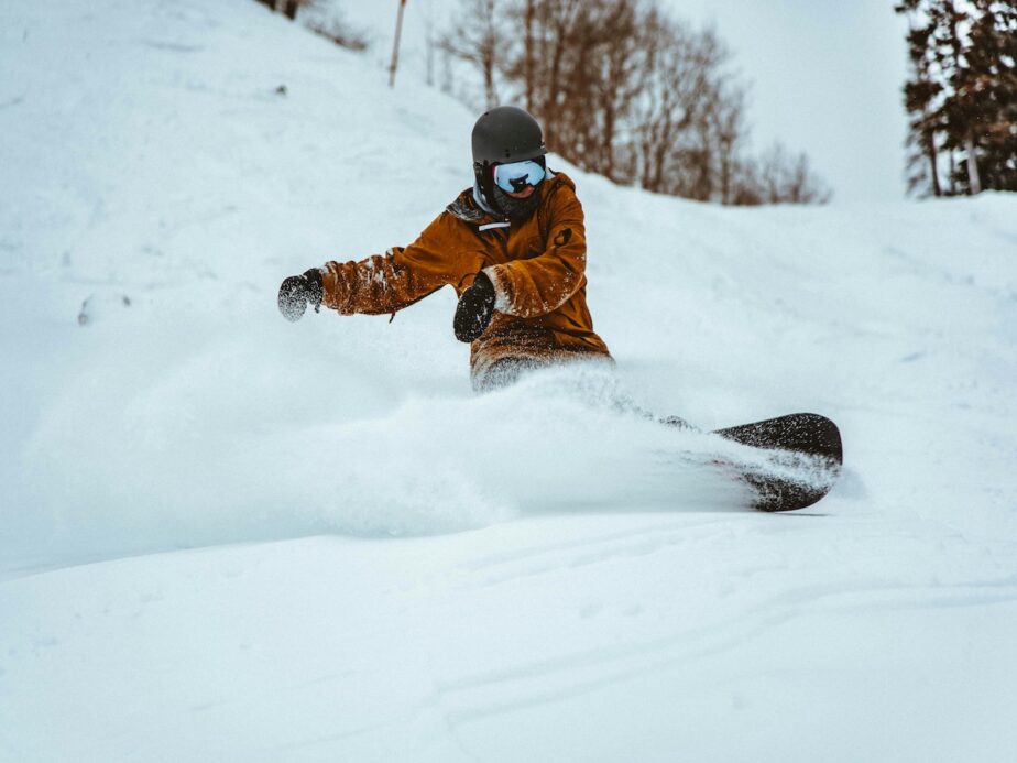 A snowboarder kicking up snow on the slopes.