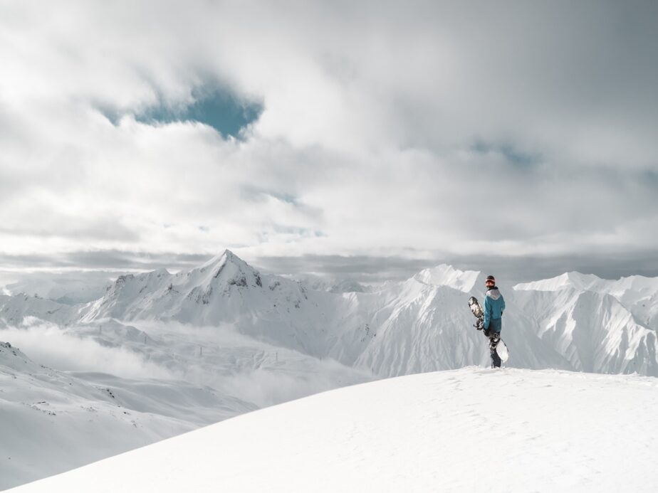 A snowboarder looking out over snowy mountains.