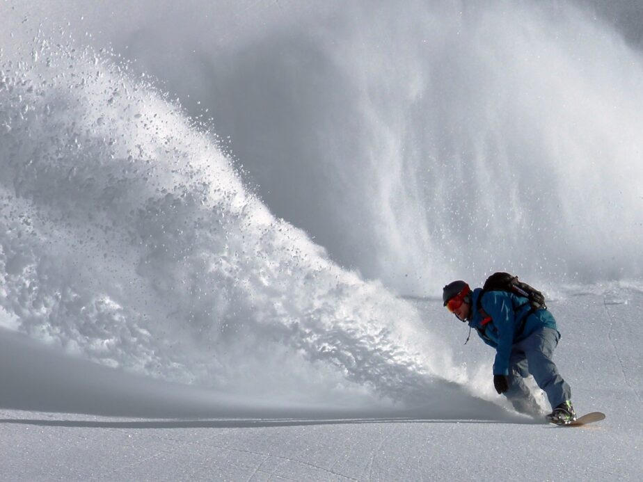 A snowboarder spraying up snow.