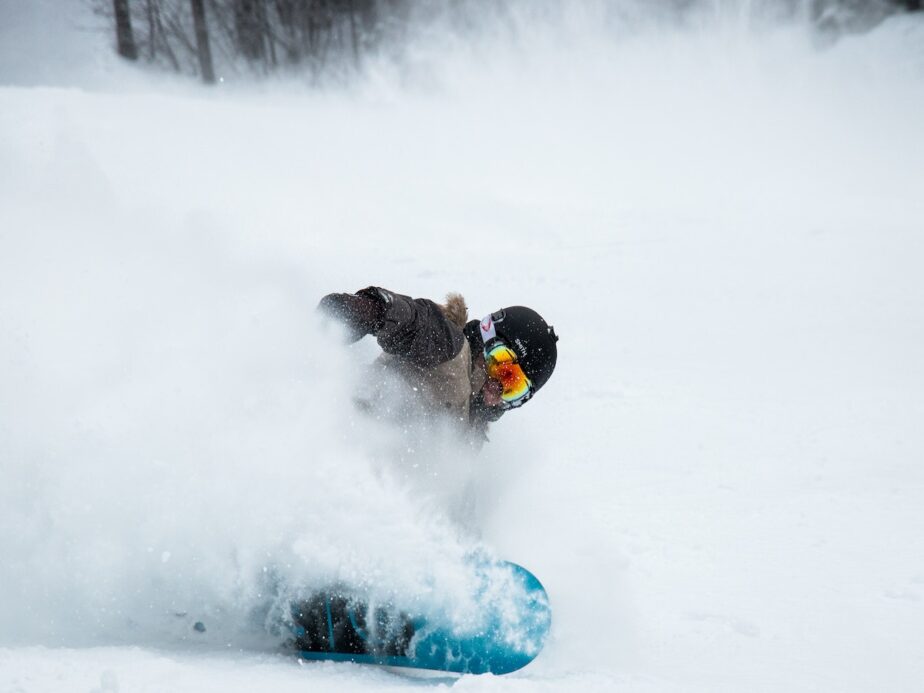 A snowboarder spraying snow on the slopes.