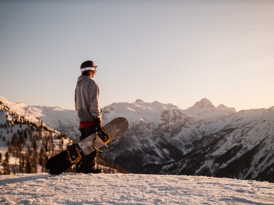 A snowboarder looking at the mountain tops.