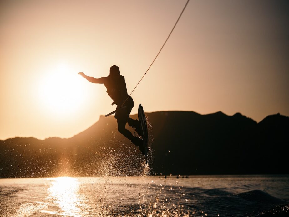 A wakeboarder jumping over the wake at sunrise.