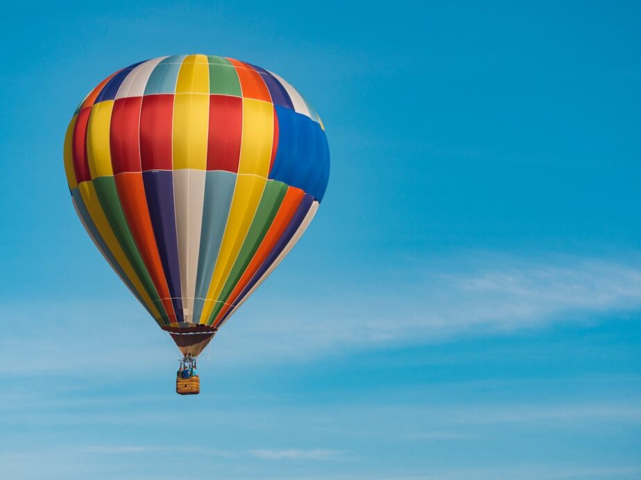 A colorful hot air balloon soaring in the air with blue skies.
