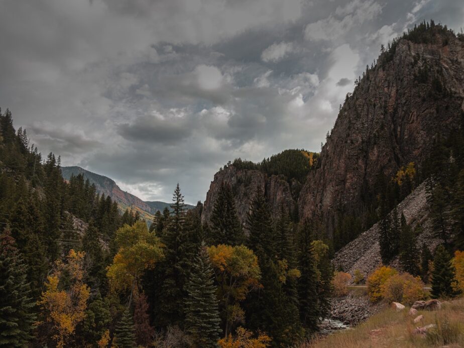 A scenic landscape in Colorado with mountains, trees, and grey skies.