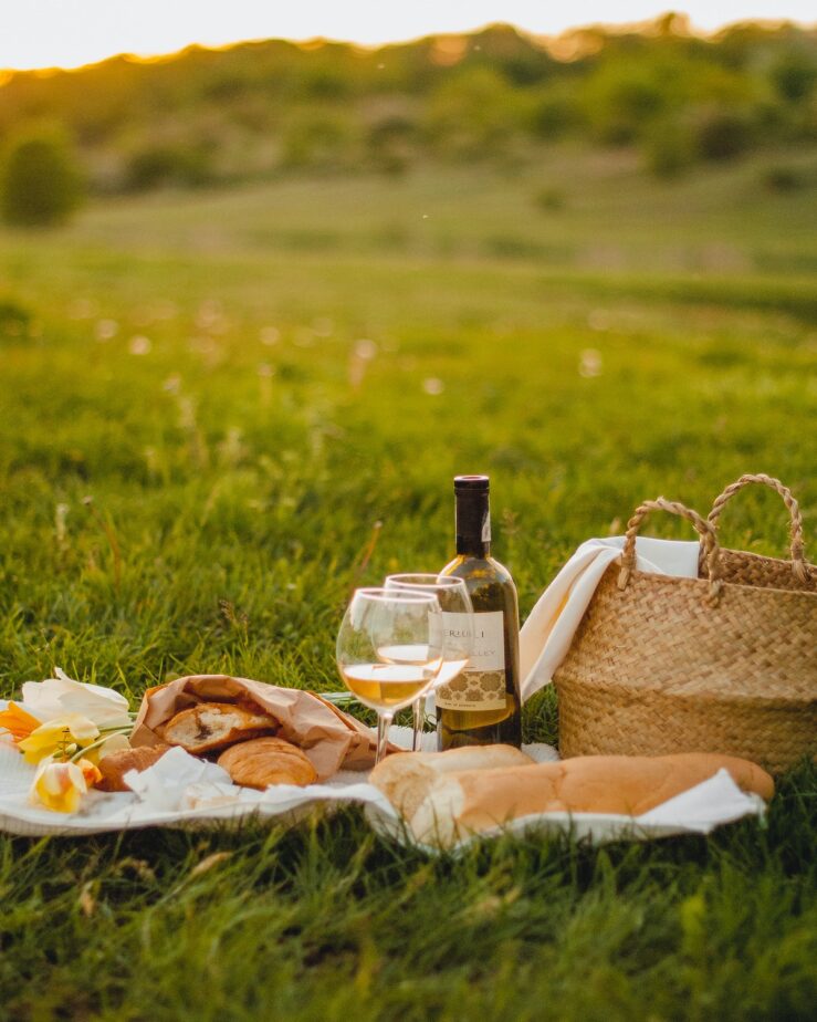 A picnic with bread and wine in a field.