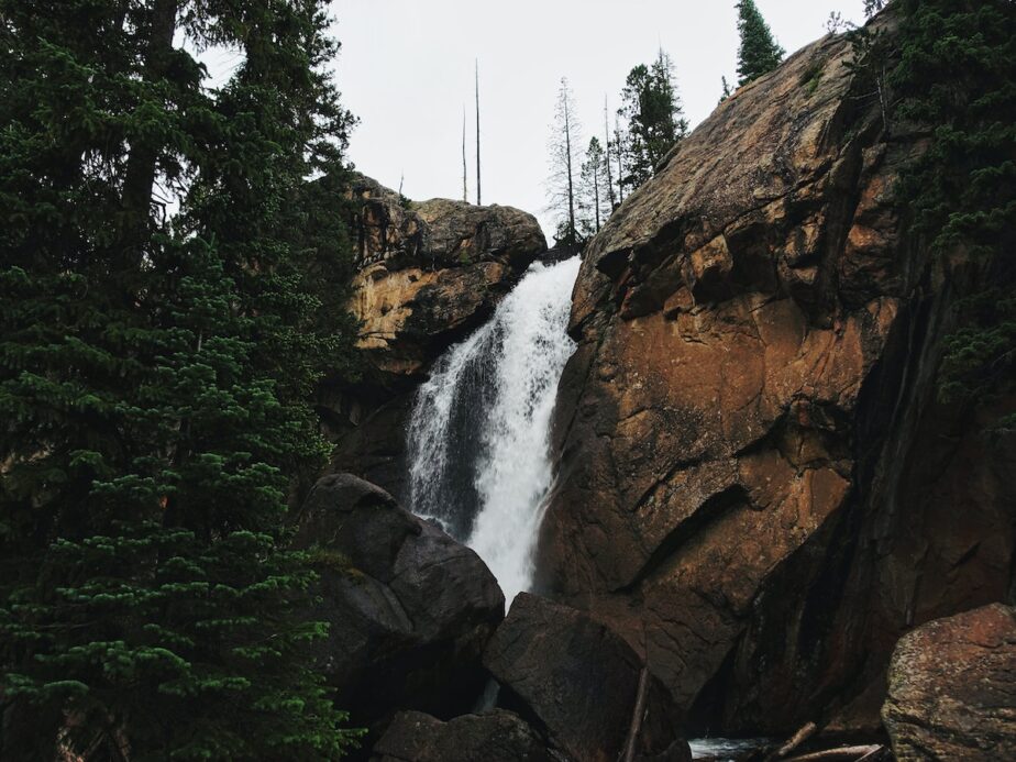 A waterfall in Colorado surrounded by rock formations and trees.