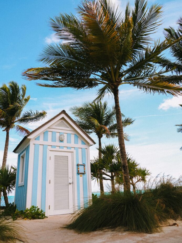 A blue and white striped building in the Bahamas surrounded by palm trees.