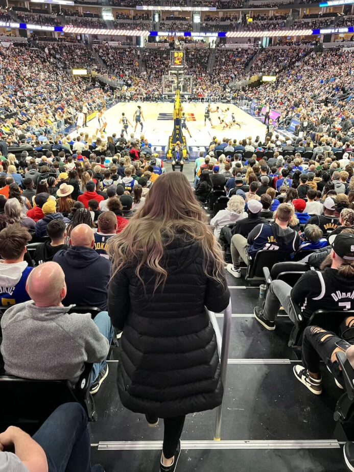 Abby walking down an aisle towards the Nuggets court.