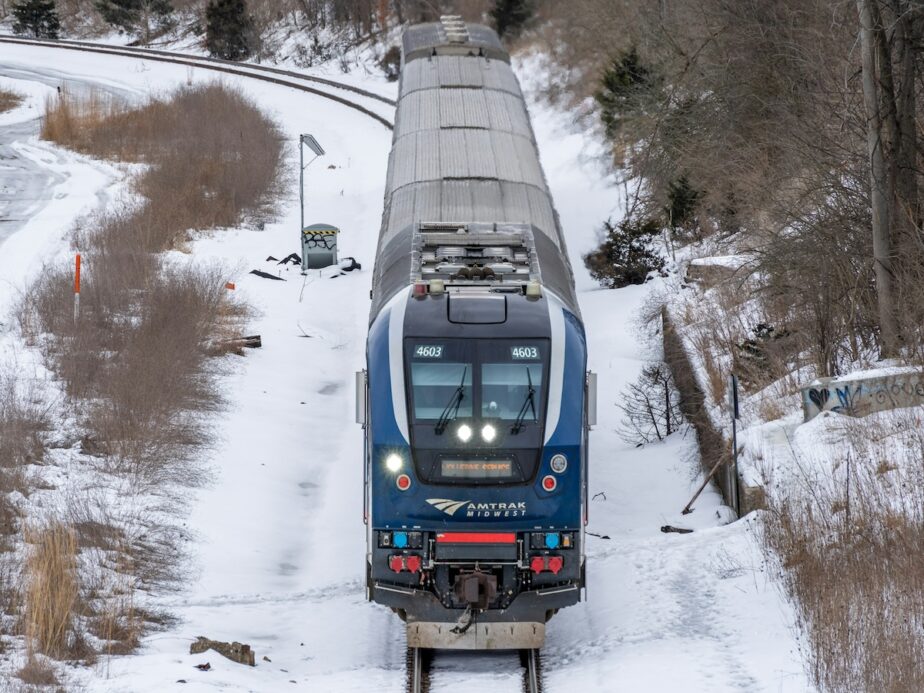 An Amtrak train traveling with snow surrounding it.