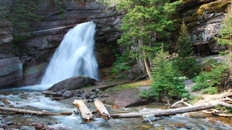 A waterfall pouring surrounded by rocks and greenery.