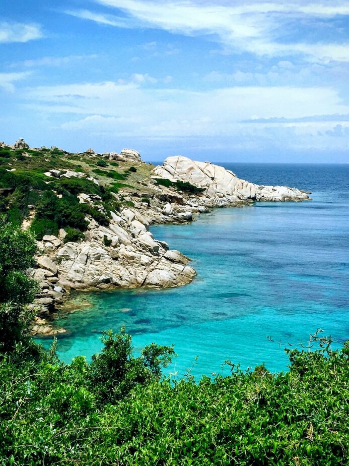 Rocky shores and greenery leading to beautiful blue water in Sardinia.