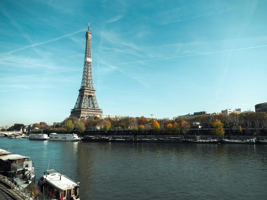 The Eiffel Tower and the Seine River with blue skies above. 